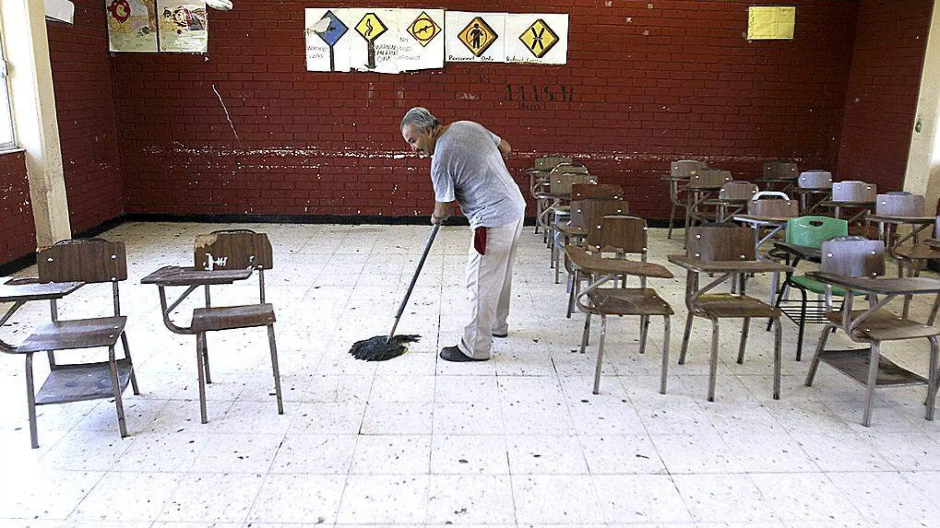 Hombre trapeando salón de clases